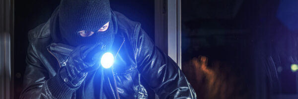 Masked burglar with crowbar breaking and entering into a house - shot with dramatic motion